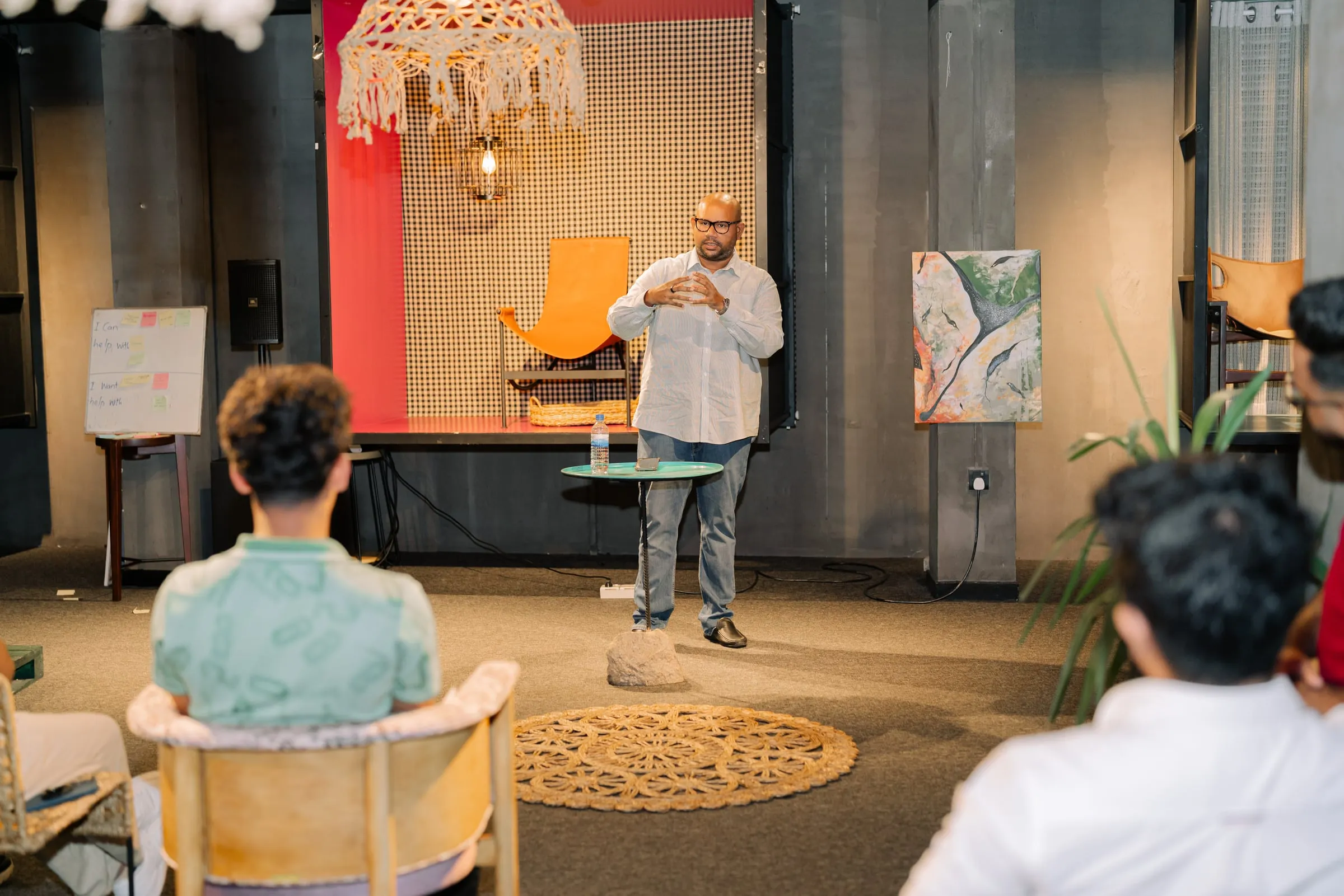 A member standing in front of a seated group, explaining something with his hands.